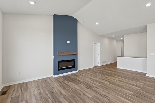 1811 Tuscany Dr SE, Altoona, IA 50009 - unfurnished living room featuring wood finished floors, vaulted ceiling, a fireplace, and recessed lighting