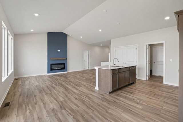 1811 Tuscany Dr SE, Altoona, IA 50009 - kitchen with stainless steel dishwasher, a center island with sink, light wood finished floors, light countertops, and vaulted ceiling