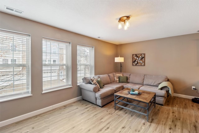 living area featuring visible vents, baseboards, and wood finished floors