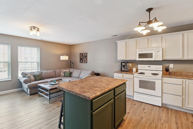 kitchen with visible vents, a kitchen island, open floor plan, light wood-style flooring, and white appliances