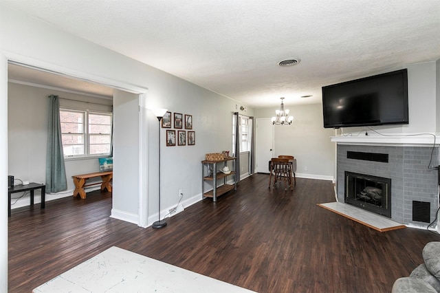 living area featuring a brick fireplace, a textured ceiling, baseboards, and wood finished floors