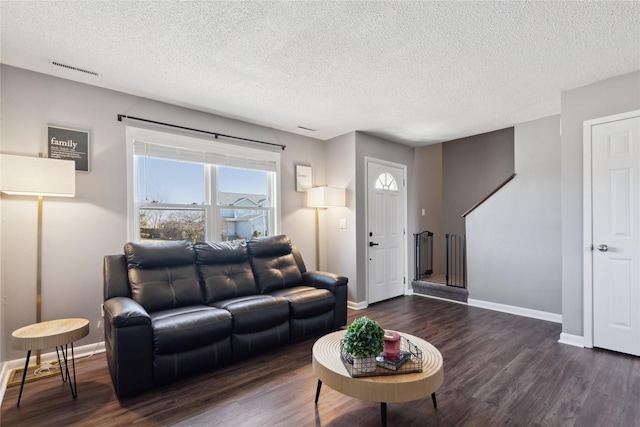 living room featuring visible vents, baseboards, dark wood-type flooring, and a textured ceiling