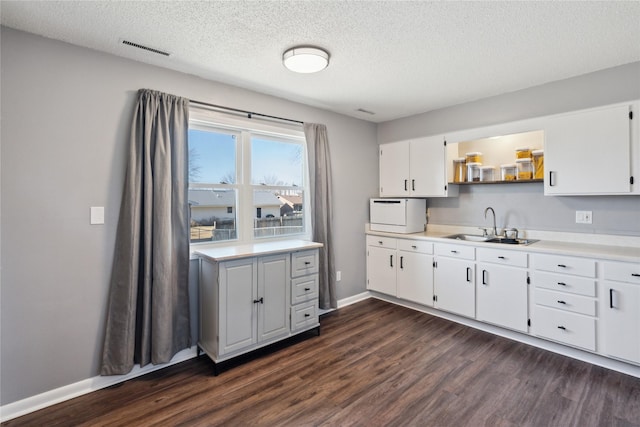 kitchen with visible vents, dark wood finished floors, a sink, light countertops, and white cabinets