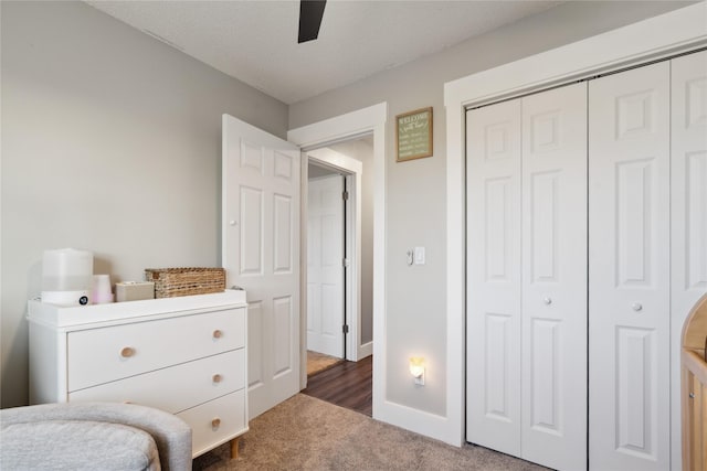 bedroom with baseboards, dark colored carpet, a closet, and ceiling fan