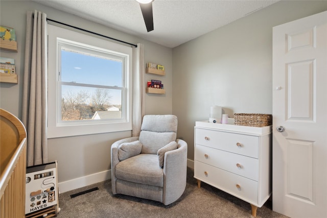 living area featuring a ceiling fan, baseboards, visible vents, a textured ceiling, and dark carpet