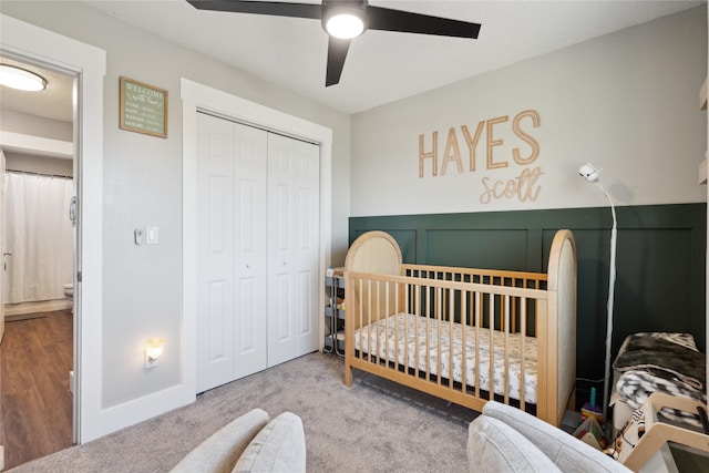 carpeted bedroom featuring a closet, a nursery area, and a ceiling fan