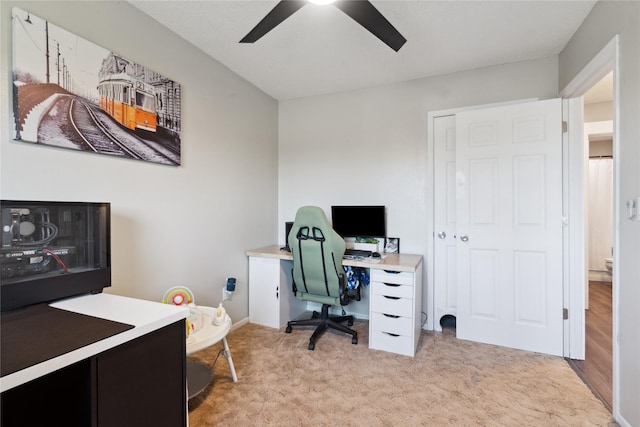 office space with a ceiling fan and light carpet