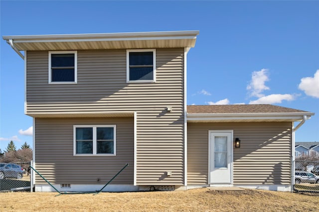 rear view of house with crawl space, roof with shingles, and fence