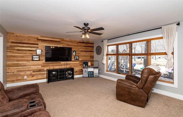 living room with wood walls, baseboards, carpet, and ceiling fan