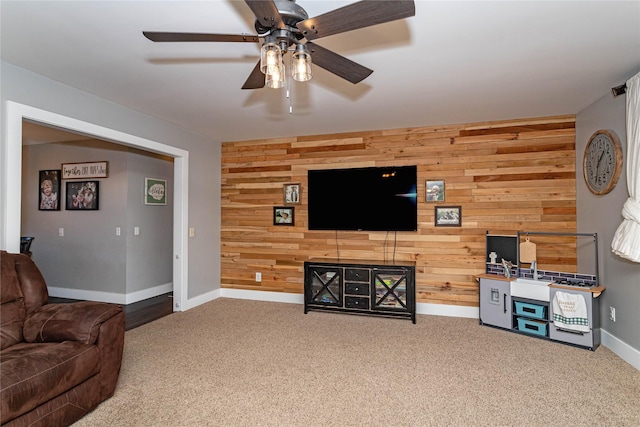 carpeted living area featuring wooden walls, a ceiling fan, and baseboards