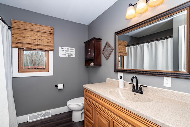 bathroom with vanity, wood finished floors, baseboards, visible vents, and toilet