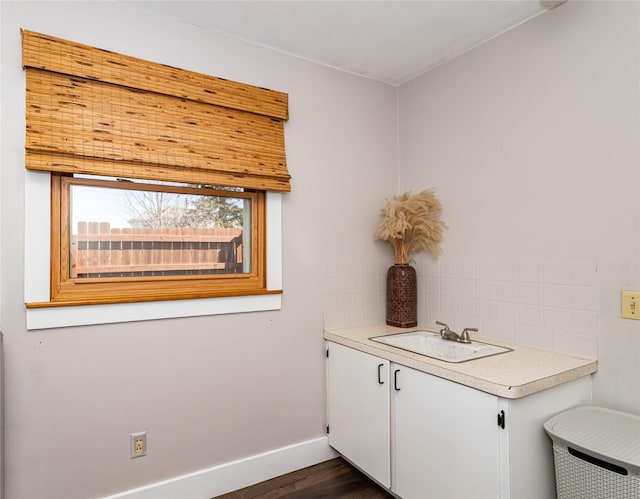 bathroom featuring vanity, wood finished floors, baseboards, and tasteful backsplash