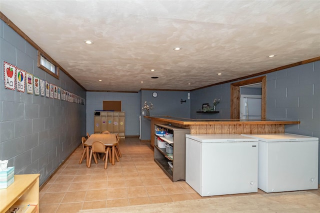 kitchen featuring recessed lighting, fridge, and concrete block wall