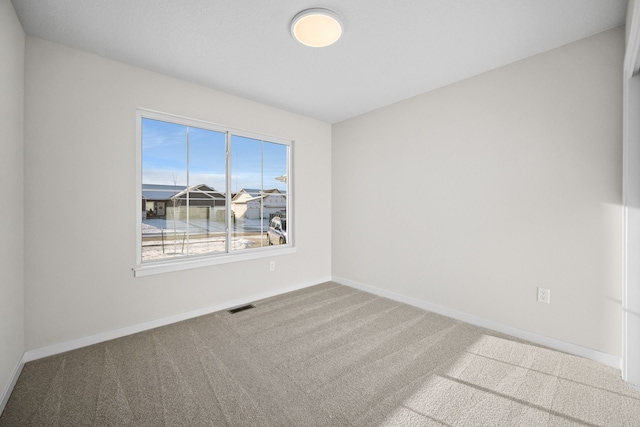 spare room featuring baseboards, visible vents, and carpet floors