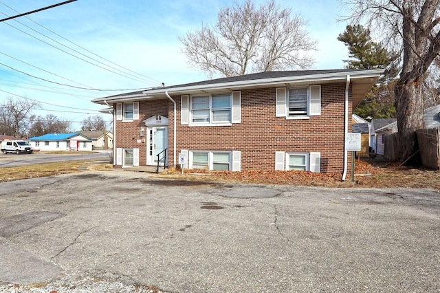 raised ranch featuring brick siding and fence