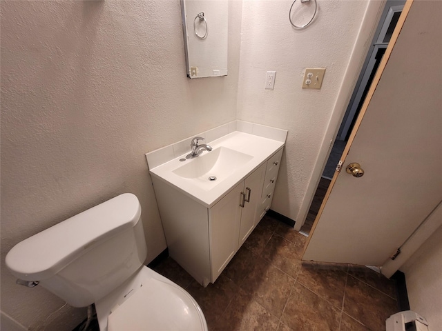 bathroom with a baseboard heating unit, toilet, vanity, and a textured wall