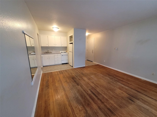 kitchen with wood finished floors, white range with gas stovetop, baseboards, and a sink