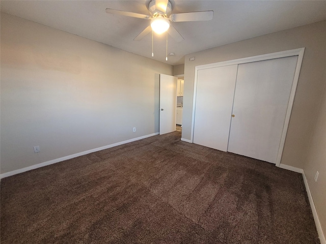 unfurnished bedroom featuring a closet, dark carpet, a ceiling fan, and baseboards