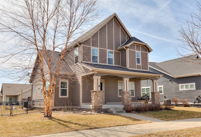 view of front facade with fence, a porch, roof with shingles, a front yard, and stucco siding