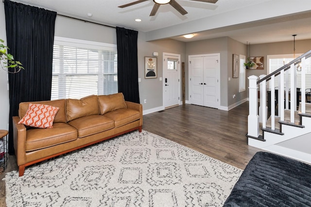 living area with a wealth of natural light, baseboards, wood finished floors, and stairs