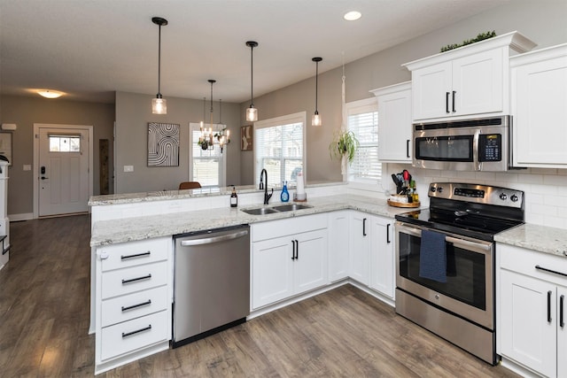 kitchen featuring a sink, dark wood-type flooring, appliances with stainless steel finishes, and a peninsula