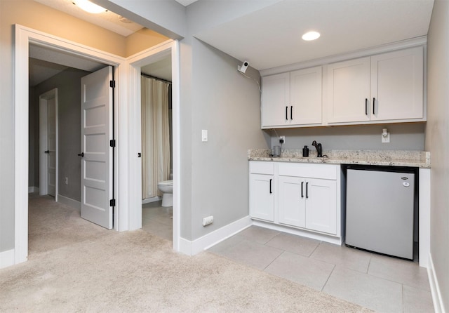 kitchen with light carpet, a sink, refrigerator, white cabinets, and light tile patterned floors