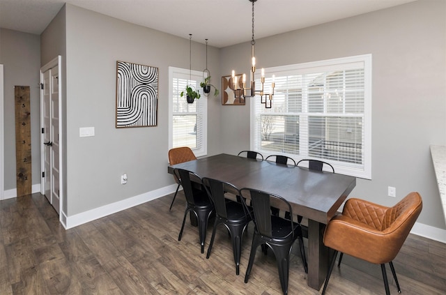 dining space featuring dark wood-type flooring, a notable chandelier, and baseboards