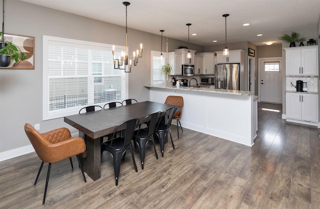 dining area with a notable chandelier, recessed lighting, wood finished floors, and baseboards