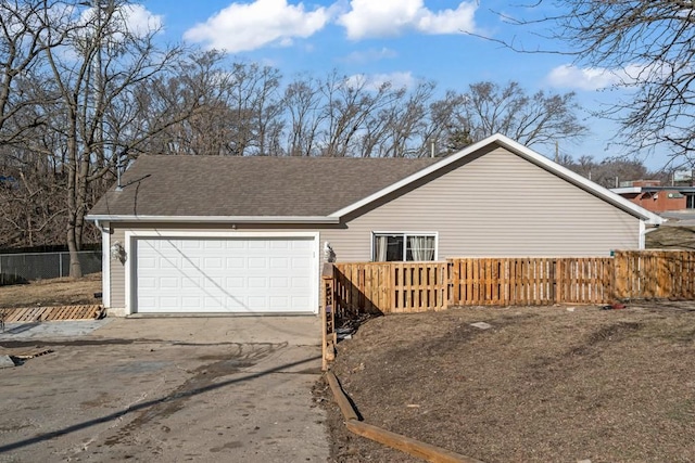 exterior space featuring fence, a garage, driveway, and roof with shingles