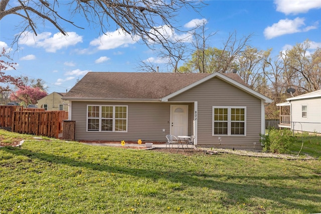ranch-style house featuring fence, a front lawn, and roof with shingles