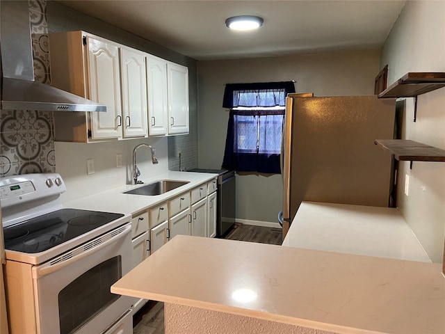 kitchen featuring freestanding refrigerator, white electric range oven, white cabinets, wall chimney exhaust hood, and a sink