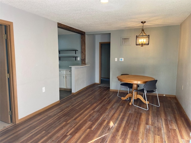 dining space featuring a textured ceiling, wood finished floors, visible vents, and baseboards