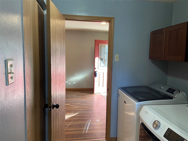 washroom with baseboards, cabinet space, light wood-type flooring, and washing machine and clothes dryer