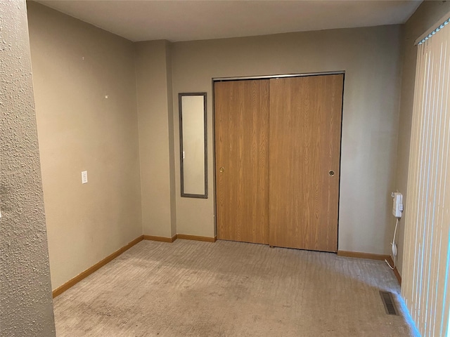 unfurnished bedroom with visible vents, carpet flooring, baseboards, and a closet