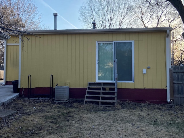 back of property with fence, central AC unit, and entry steps