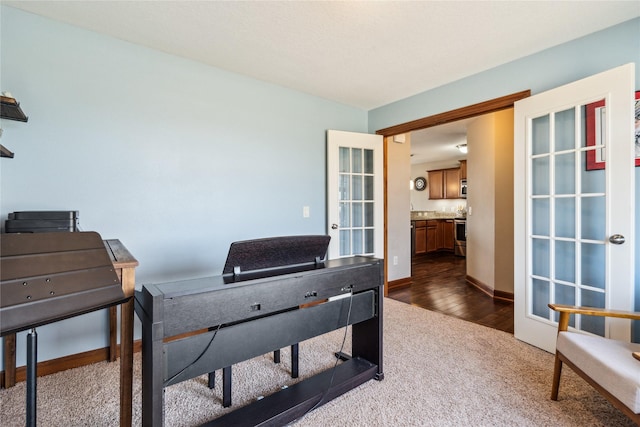 office area featuring dark wood finished floors, french doors, baseboards, and dark colored carpet