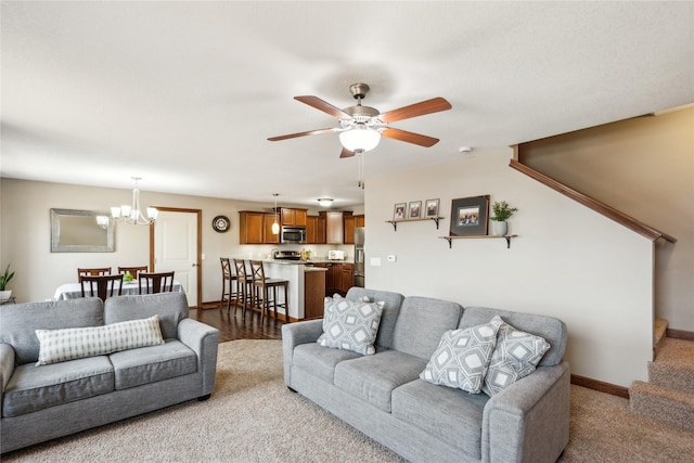 living room with stairway, ceiling fan with notable chandelier, and baseboards