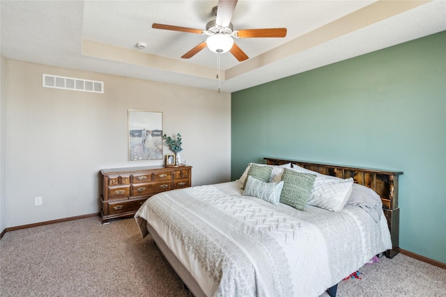 bedroom featuring a tray ceiling, baseboards, visible vents, and carpet floors