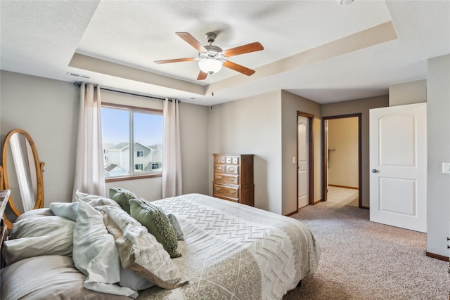 carpeted bedroom featuring visible vents, ceiling fan, a raised ceiling, and baseboards