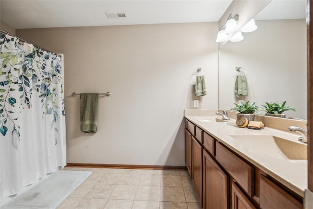 bathroom featuring tile patterned flooring, double vanity, visible vents, and a sink