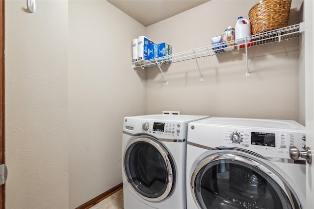 washroom featuring washing machine and clothes dryer, laundry area, baseboards, and light tile patterned floors