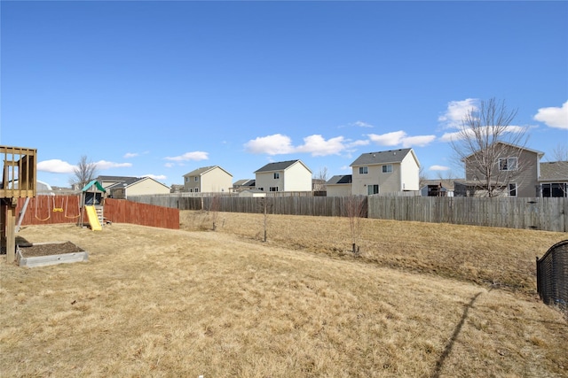 view of yard featuring a playground, a fenced backyard, and a residential view