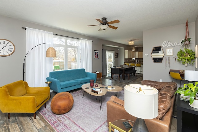 living room with a textured ceiling, ceiling fan, and wood finished floors