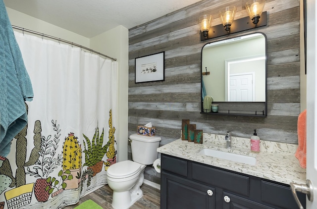 bathroom featuring wood walls, toilet, a shower with shower curtain, wood finished floors, and vanity