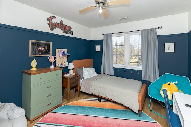 bedroom featuring visible vents, a ceiling fan, and wood finished floors