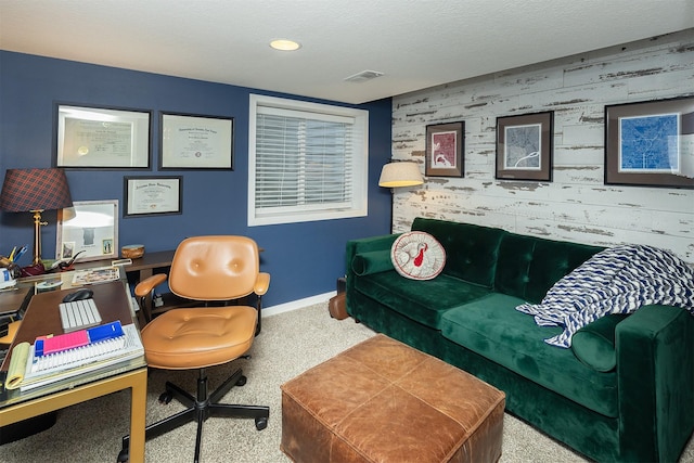 carpeted office space with an accent wall, baseboards, visible vents, and a textured ceiling