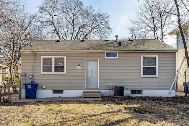 rear view of property featuring entry steps, central AC unit, and fence