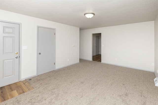 empty room featuring carpet, baseboards, and a textured ceiling