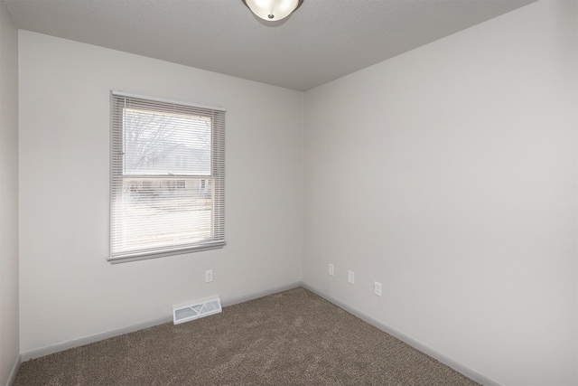 carpeted empty room featuring visible vents and baseboards