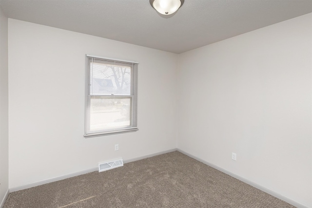 carpeted spare room with visible vents and baseboards